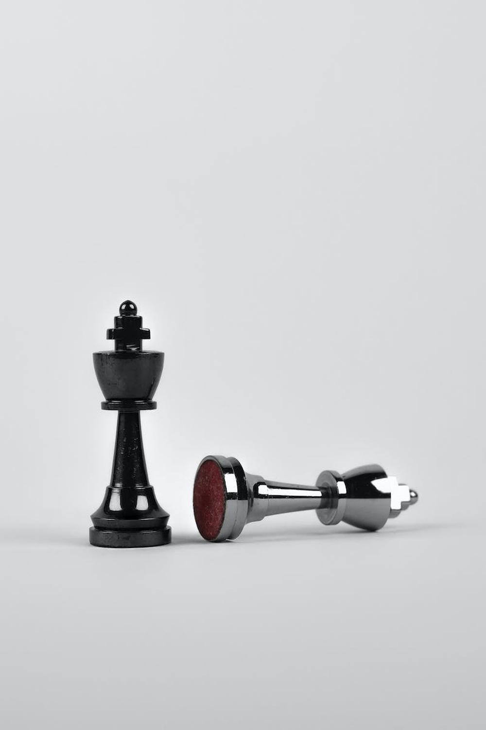 two_silver_chess_pieces_on_white_surface